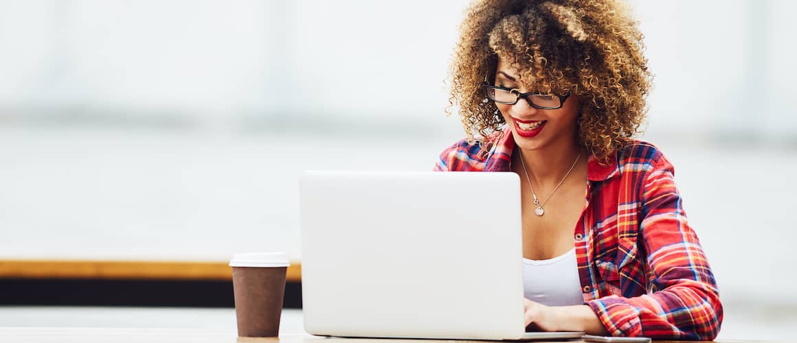 A woman wearing glasses working on a laptop, indicating digital work or studying.