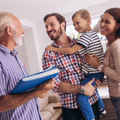 A family in a living room, with an old man holding a clipboard, possibly discussing or organizing something.