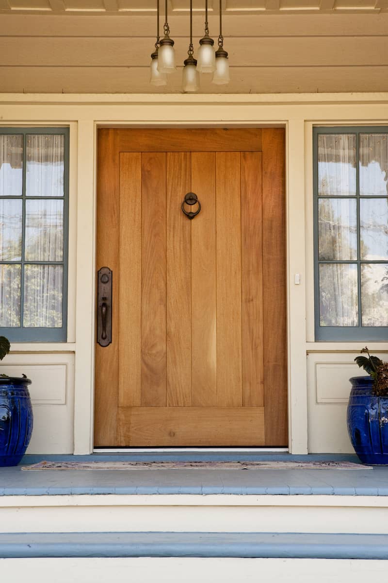 RHB Assets From IGX: Rustic wooden front door with an ornate metal handle and glass window.