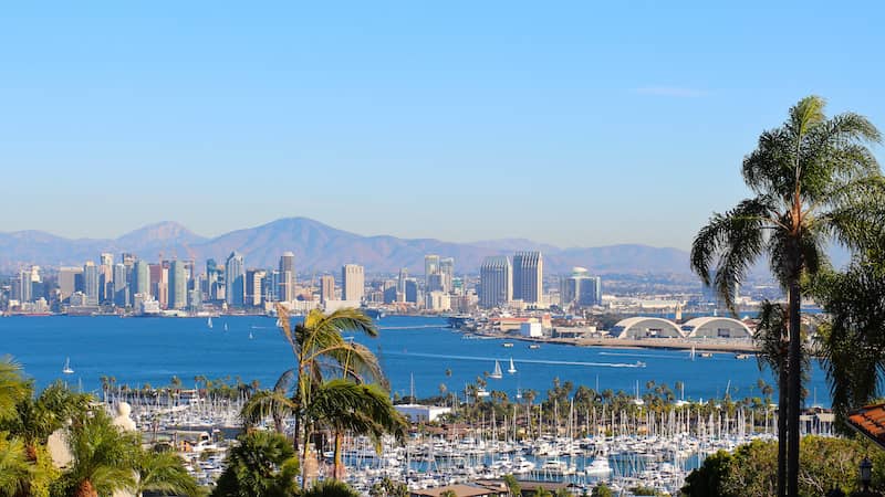 RHB Assets From IGX: Aerial view of the San Diego, California coastline with clear blue skies and ocean waves.