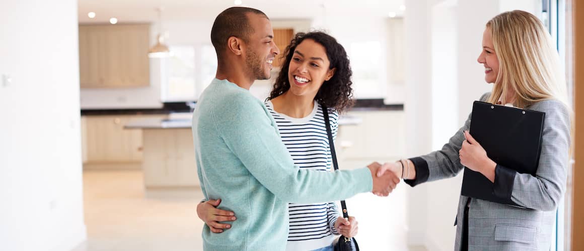 Happy couple shaking hands with their real estate agent.