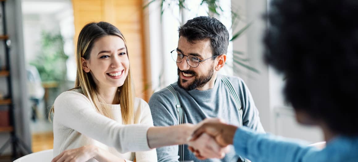 A couple in a meeting shaking hands.