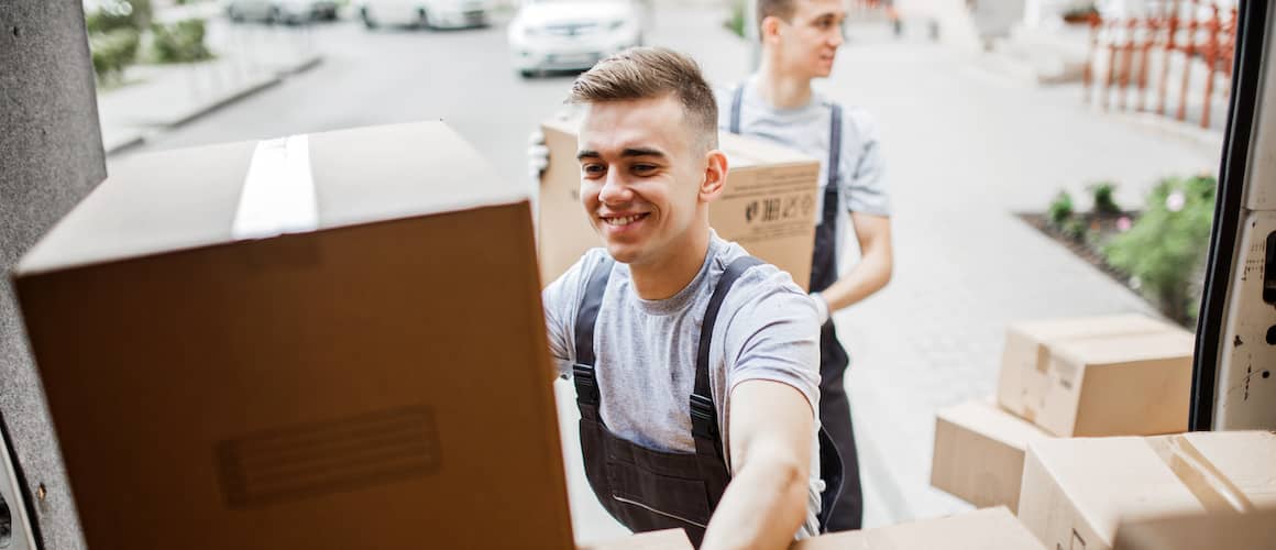 two young men moving stuff from van to house