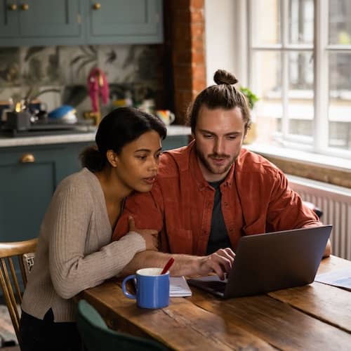 Young couple studying their finances at their kitchen table.