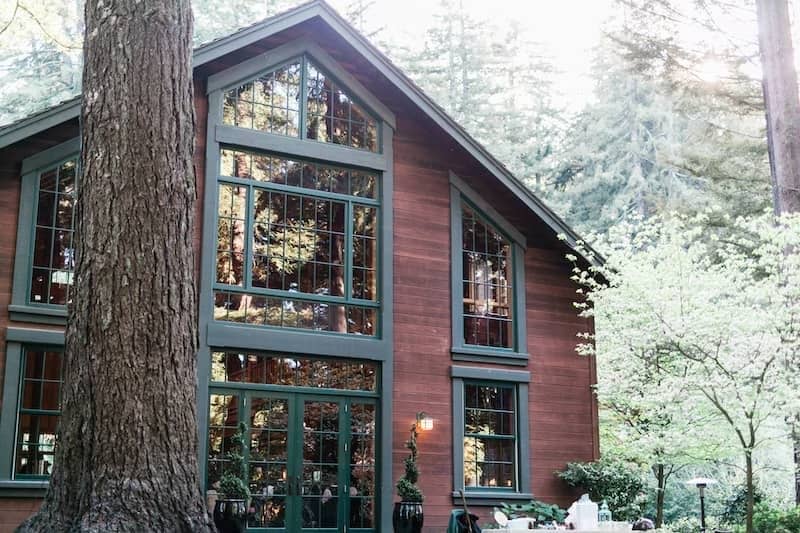 Converted barn with wall of windows nestled in woods.