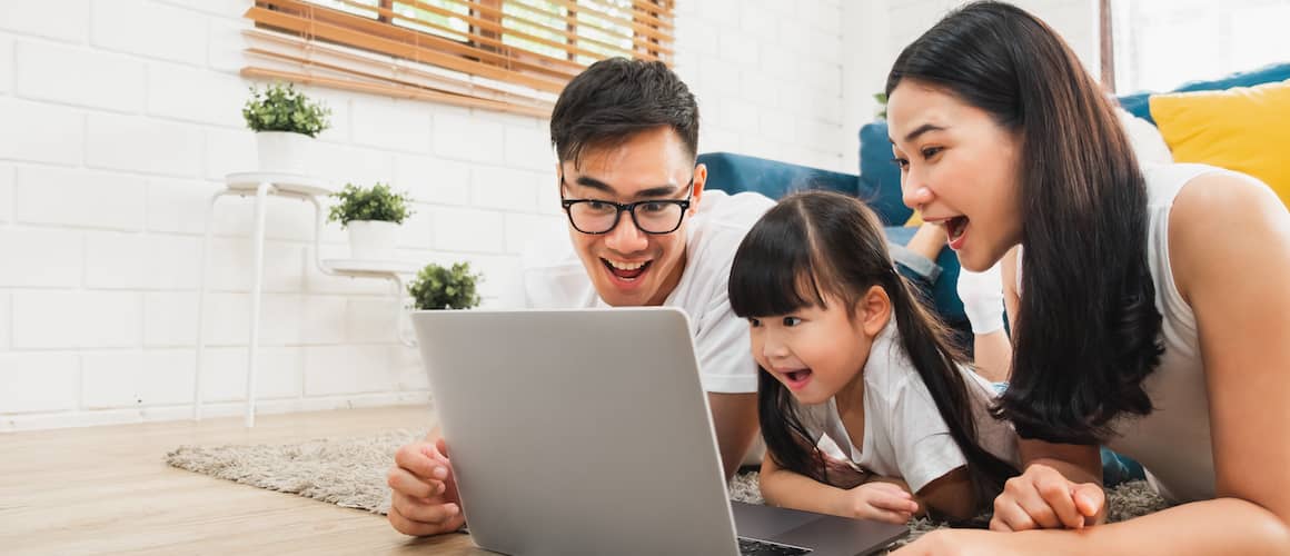 A happy family of three gathered around a laptop, enjoying quality time together while browsing online.