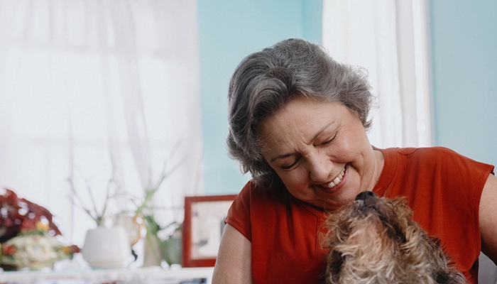 Woman Smiling and petting dog on couch.