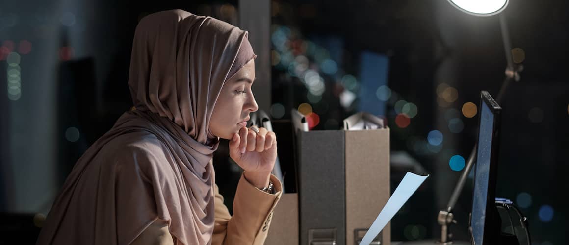 A woman in a hijab looking at papers, possibly related to homeownership or finances.