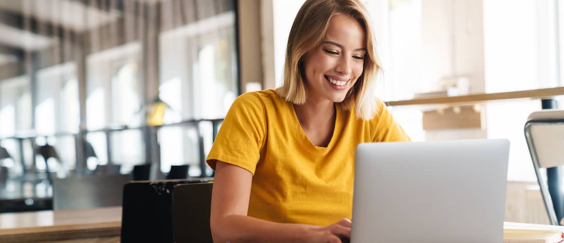 Woman smiling while reviewing options online on her laptop.