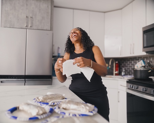 Woman in kitchen laughing.