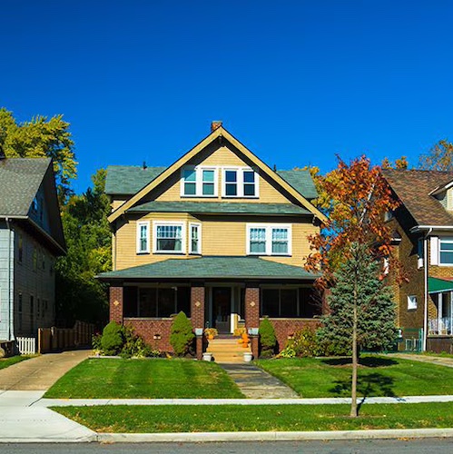 Yellow house with brick porch.