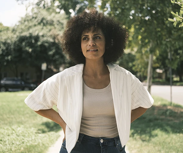 A woman stands with her hands on her hips.