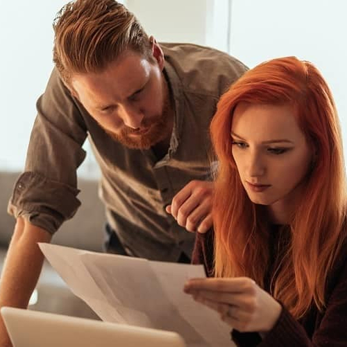 A young couple reviewing paperwork together, possibly related to a mortgage or property.