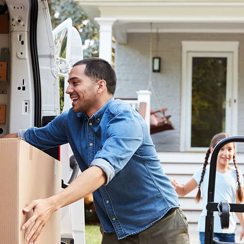 A family unloading boxes from a vehicle to move into their new house.