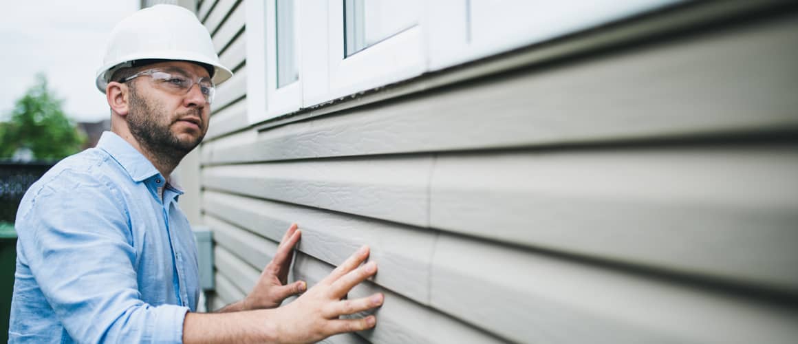 An image showing a building inspector checking windows of a building, related to an article or content discussing inspection or regulatory compliance.