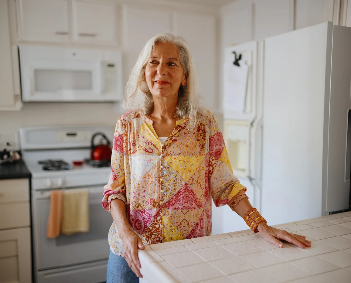 Older woman standing in a kitchen by a countertop
