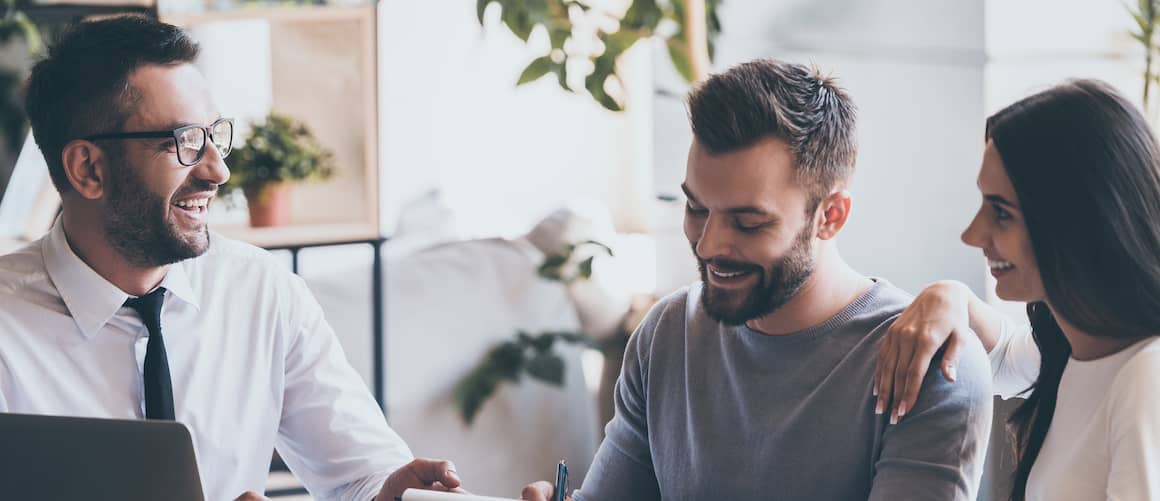 Loan officer reviewing mortgage paperwork with smiling couple.