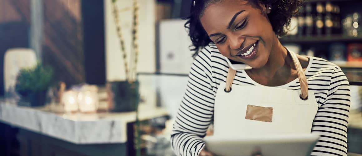 African American woman small business owner taking reservations over the phone and inputting into her tablet.