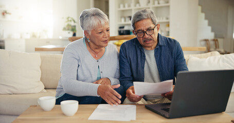 Retired couple on couch researching loan options on laptop.