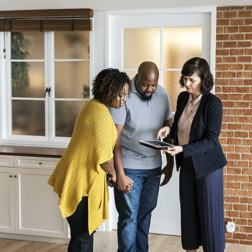 Couple exploring a new home with a realtor, examining or considering a property.