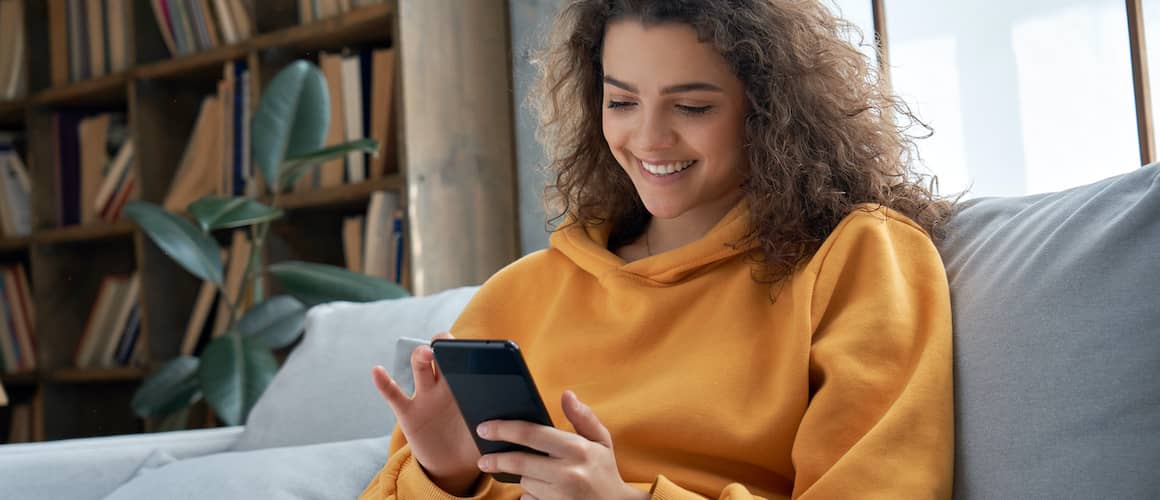 RHB Assets From IGX: Millennial Hispanic teenage girl holding smartphone at home