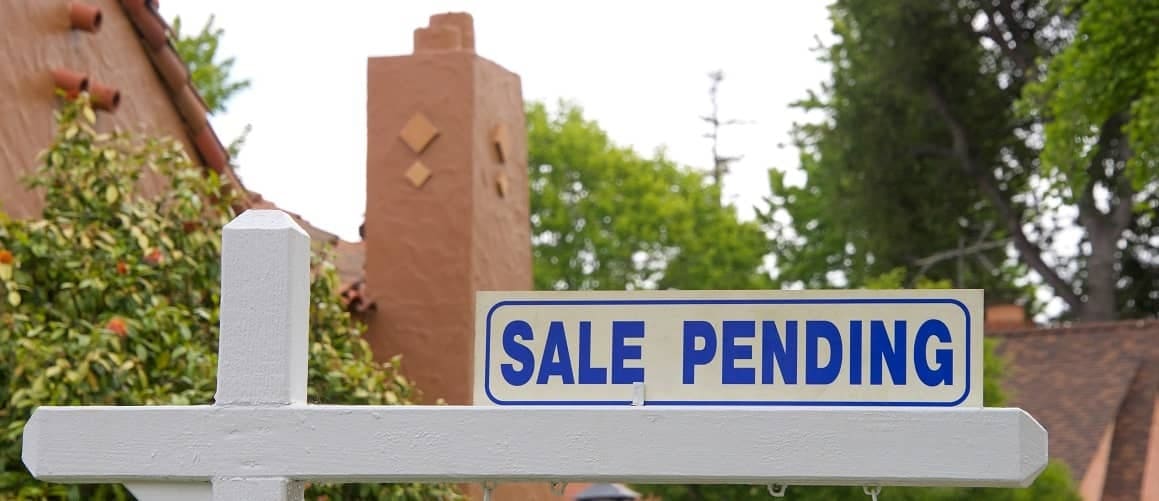 A "Pending Sale" sign in front of a house, indicating it's under contract or in the process of being sold.