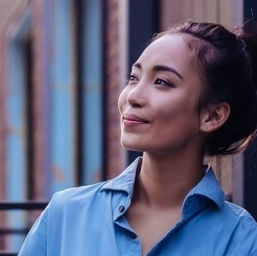 A woman in a blue shirt enjoying the view from her balcony.