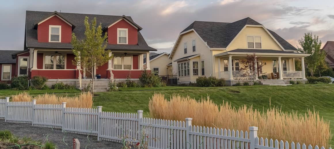 RHB Assets From IGX: Wooden fence marking a property line with a lush green lawn and trees.