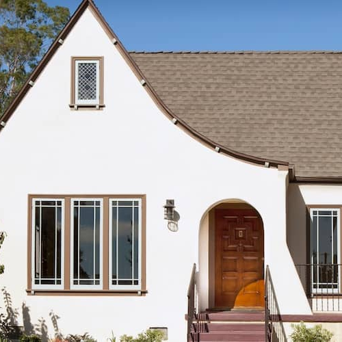 White stucco bungalow with sloped roof and red door.