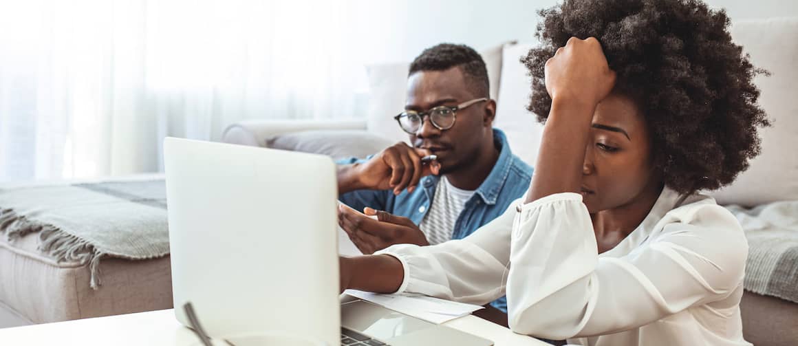 Stressed out couple looking at their expense sheets on computer.