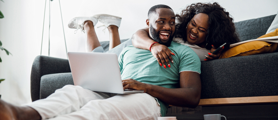 Happy young black couple smiling to each other on a couch