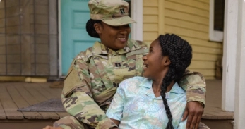 Veteran hugging family member in home with folded American flag in the background.