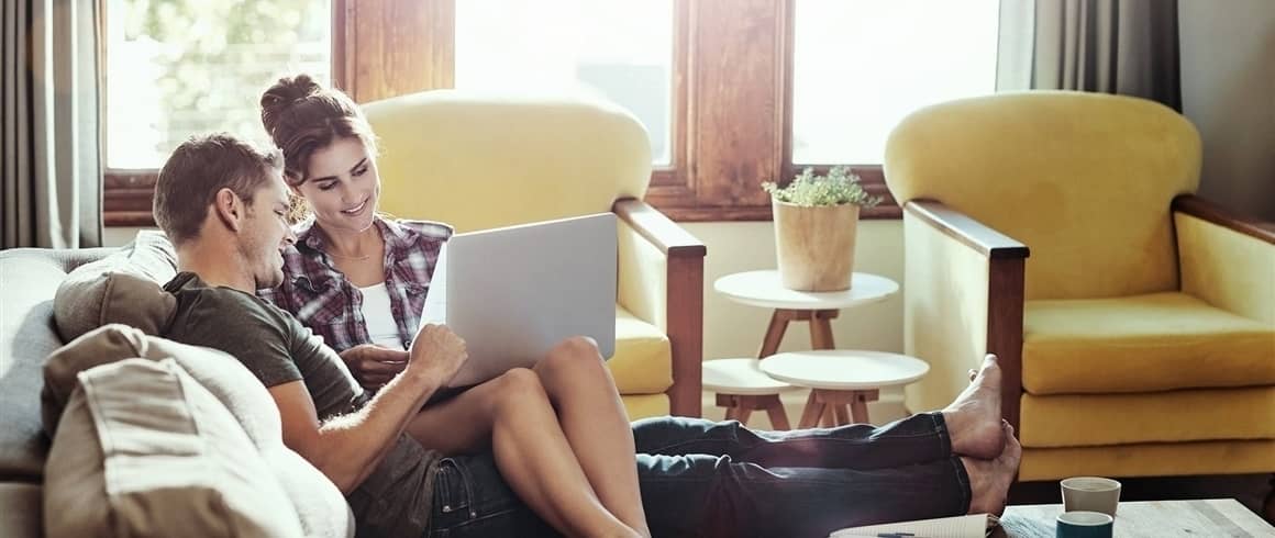 Young couple laying on couch together.