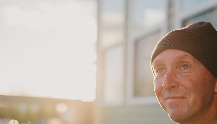 Man with hat smiling in setting sun.