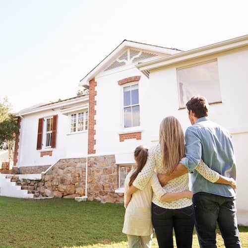 Young family admiring their new home from the front yard.