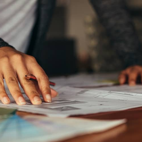 Documents spread across a table alongside a coffee mug, portraying an organized or busy setting related to home paperwork or financial documentation.