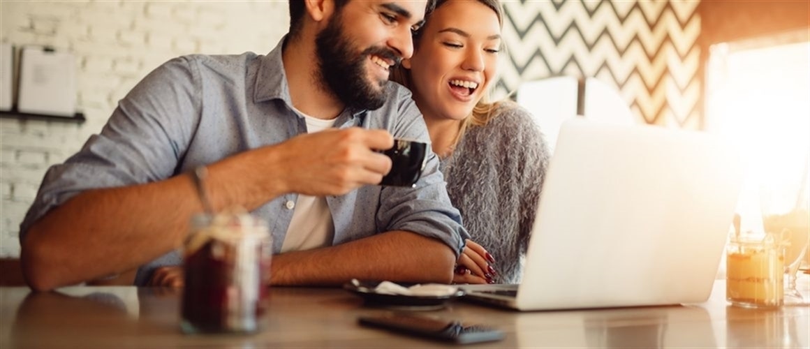 Image of couple on laptop in coffee shop, reviewing debt options.