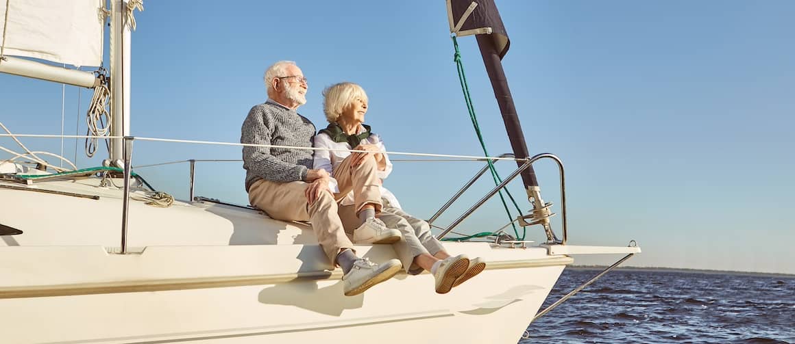 Retired couple on bow of sailboat in the ocean.