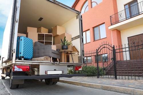 Moving van filled with boxes in front of townhomes.