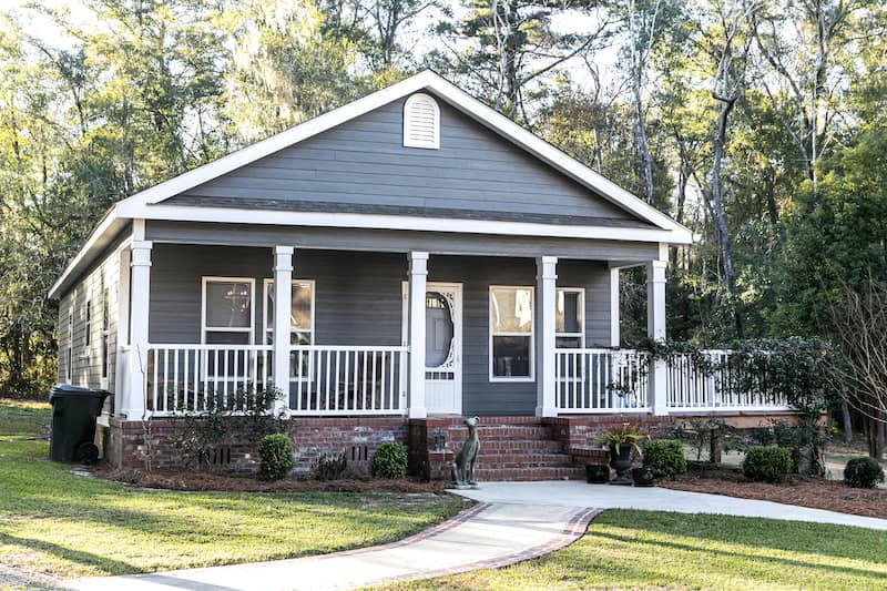 Grey, prefabricated house with large porch.