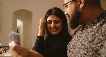 Couple smiling at each other while playing a card game.