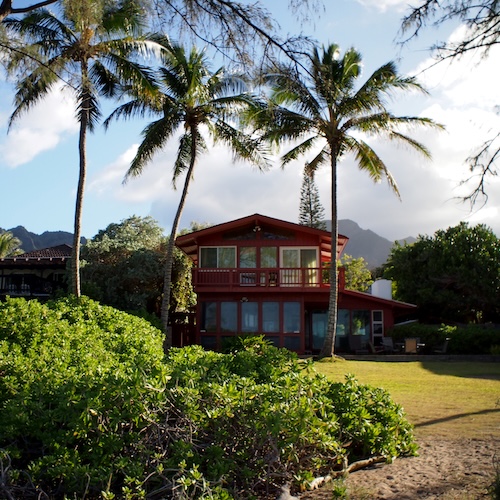 Large house with many windows and palm trees in Hawaii.