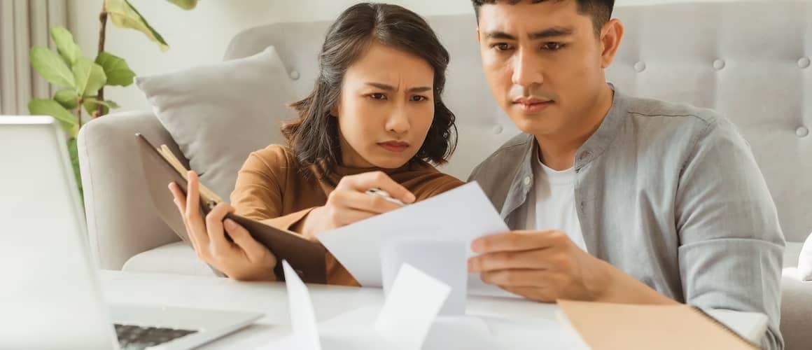 Couple looking at bills together and frowning.