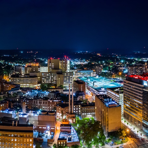 Aerial cityscape view of New Haven at night with lit up buildings.