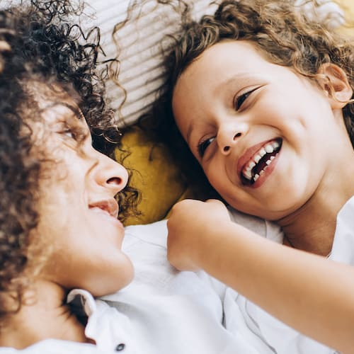 Two girls smiling and laughing on a bed.