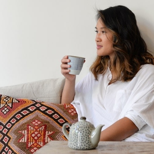 Woman drinking tea on her couch.