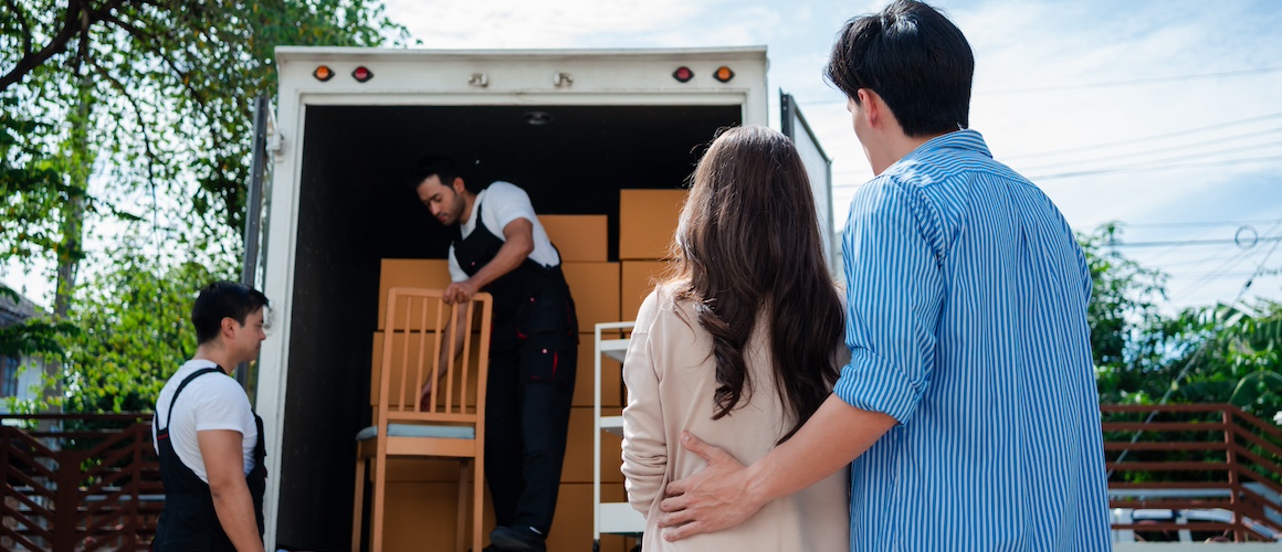 Young couple being assisted by two movers as they load up a moving van.