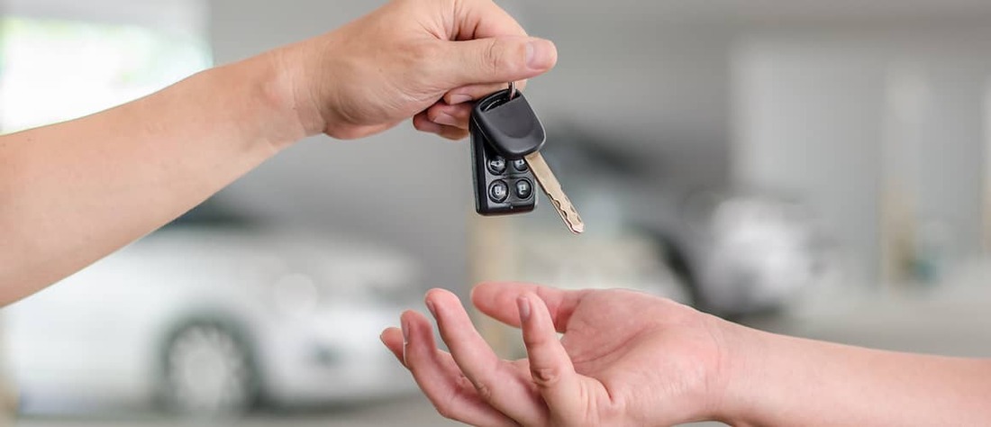 Close up view of a person's hand dropping car keys into another person's hand.