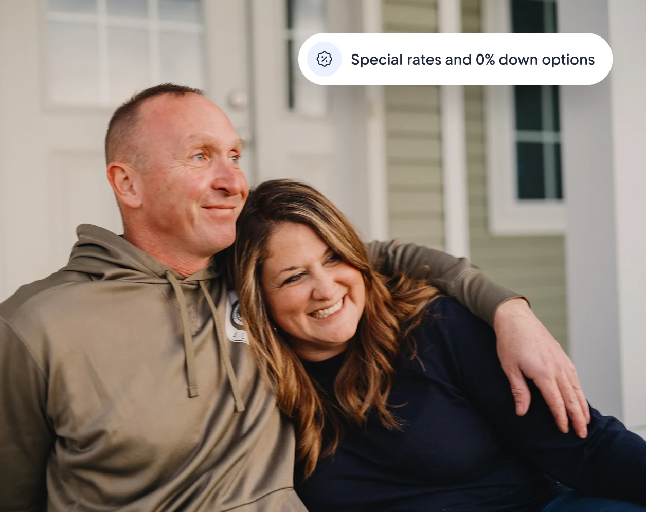 Smiling couple sitting together on their front steps, with text reading "Special rates and 0% down options."