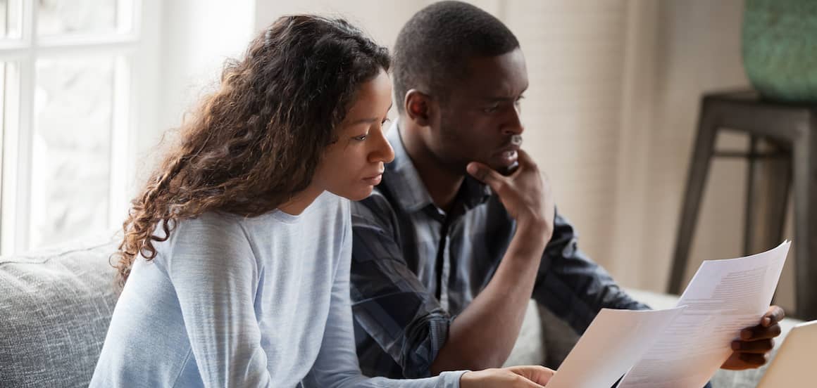 African American couple reading paperwork together.